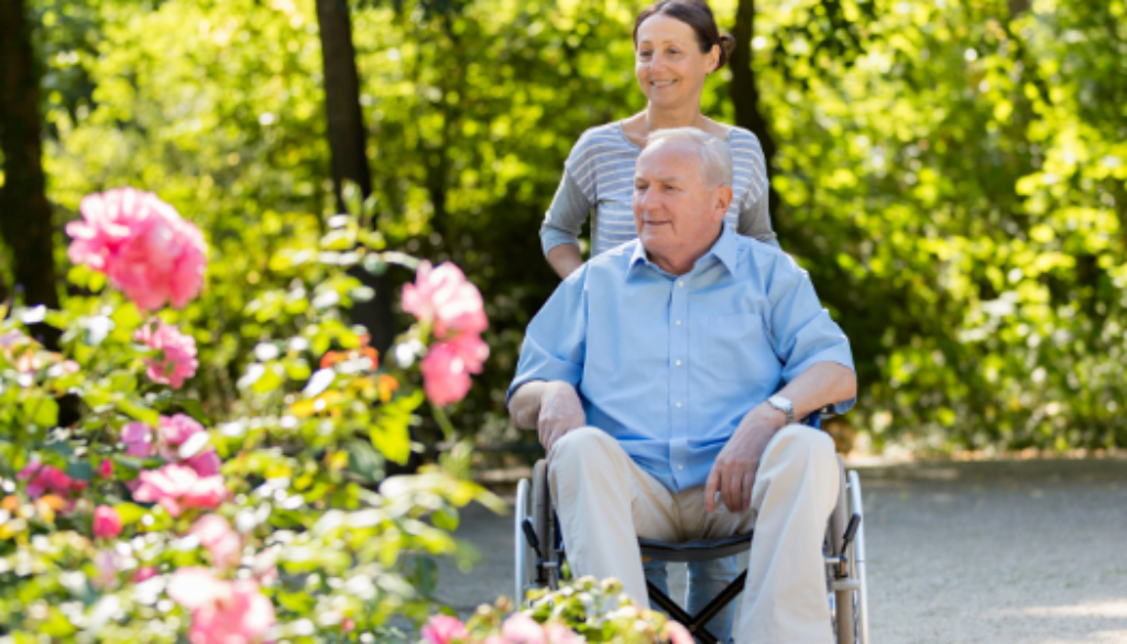A caregiver enjoying a walk with their loved one in a wheelchair.