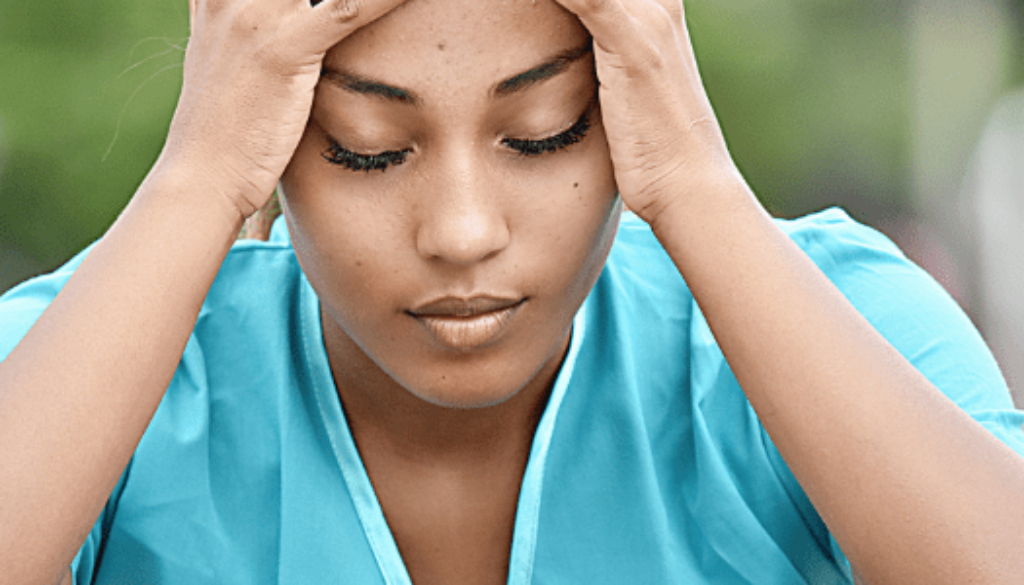 Woman with her hands on her head and eyes closed stress for Nursing shortage