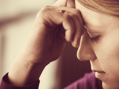 Woman with a hand on her forehead with caregiver guilt